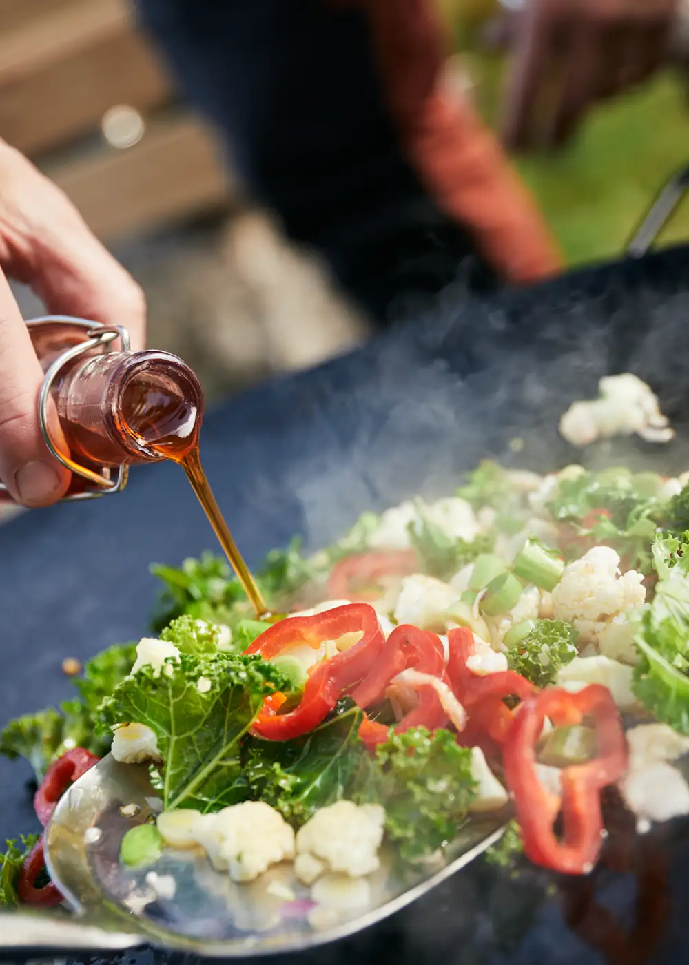 Lokala grönsaker tillagas på stekhäll över öppen eld utomhus.