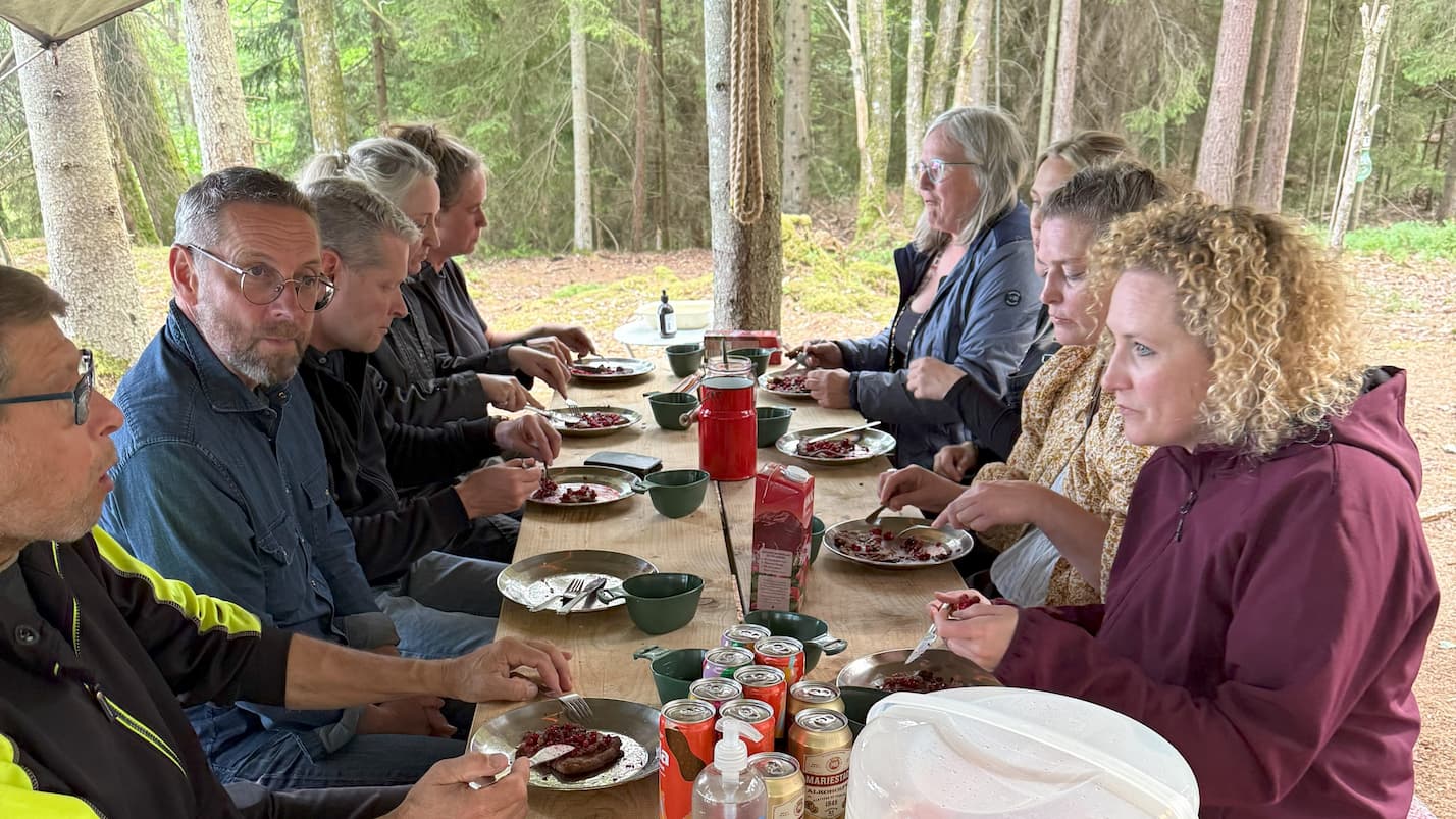 Personer som sitter vid ett bord och äter tillsammans utomhus.