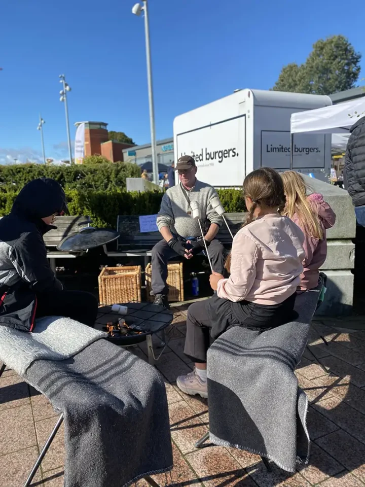 Peter Carlsson sitter vid en grillplats där barn grillar marshmallows under vårmarknaden i Gråbo.