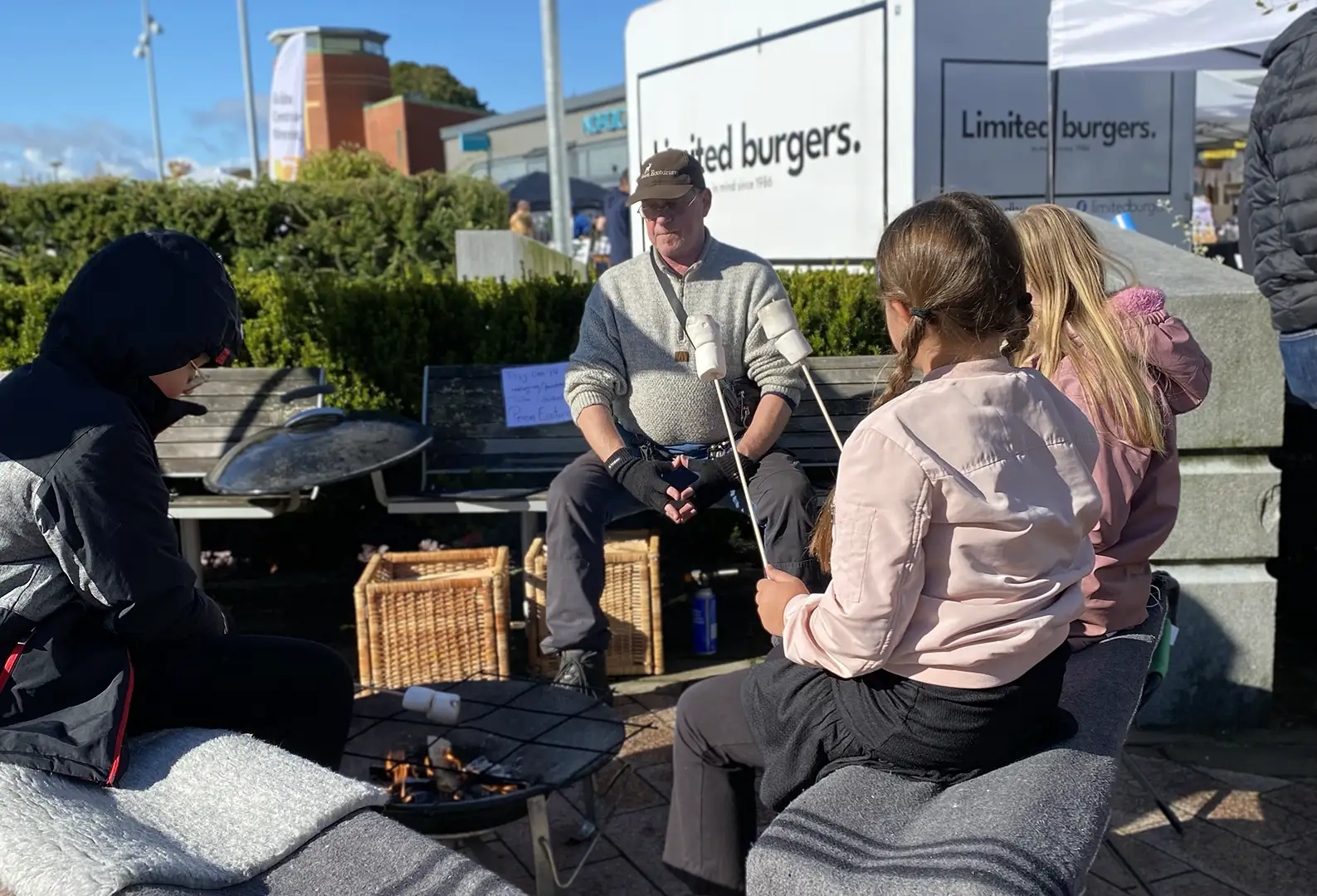 Peter Carlsson sitter vid en grillplats där barn grillar marshmallows under vårmarknaden i Gråbo.